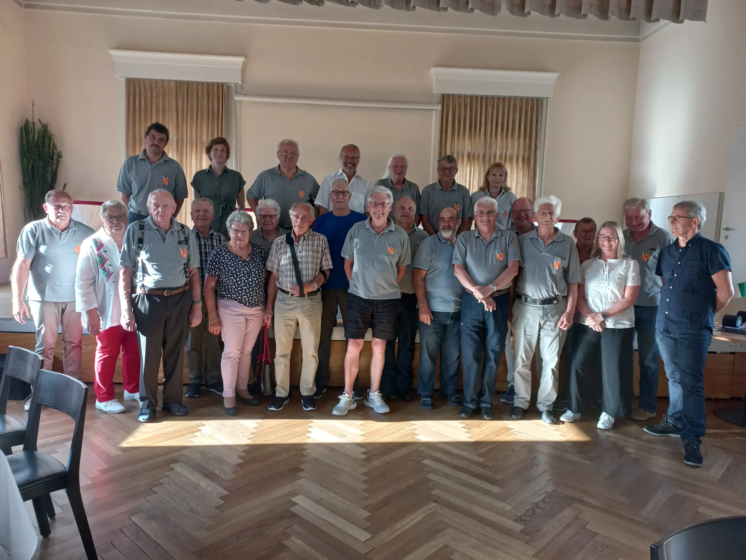 Vorstandsmitglieder/-innen und Fahrer/-innen des Vereins Rollmobil March-Höfe, die in einem Saal stehen