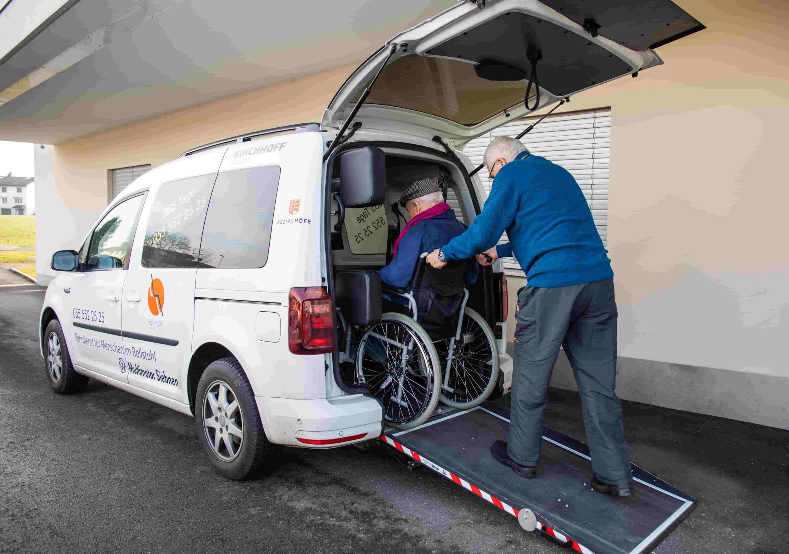 Freiwilliger von rollmobil March Höfe schiebt Rollstuhlfahrer in das Auto